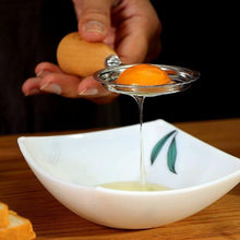 Load image into Gallery viewer, Person squeezing an orange over a white bowl with a leaf design on a wooden surface.
