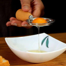Load image into Gallery viewer, Person squeezing an orange over a white bowl with a leaf design on a wooden surface.