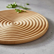 Load image into Gallery viewer, Wooden cutting board with concentric circular pattern on a gray surface