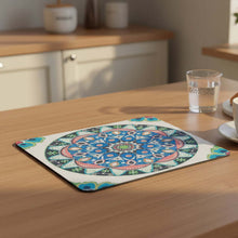 تحميل الصورة في عارض المعرض، Colorful mandala placemat on a wooden table with a glass of water and cup in the background.