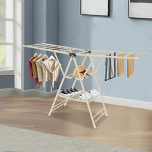 تحميل الصورة في عارض المعرض، Clothes drying rack with clothes and shoes inside a room with blue walls and a window.