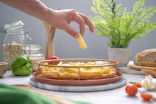 تحميل الصورة في عارض المعرض، Person placing a yellow vegetable into a wire basket on a kitchen counter with various items in the background.