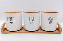 Load image into Gallery viewer, Three ceramic canisters labeled 'Coffee', 'Tea', and 'Sugar' on a wooden tray with a white background.
