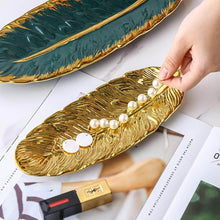 تحميل الصورة في عارض المعرض، Gold leaf-shaped tray with pearls on a white surface with a magazine underneath.
