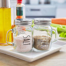 Load image into Gallery viewer, Vintage glass salt and pepper shakers set with stainless steel lids and handles on a kitchen counter.