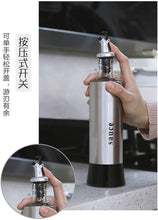 Load image into Gallery viewer, Hand holding a stainless steel and glass sauce dispenser with a push button top, ideal for oil and vinegar.