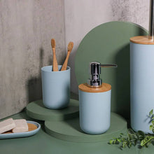 تحميل الصورة في عارض المعرض، Bathroom setting with blue containers, wooden toothbrush holder, and soap dispenser on a green surface.
