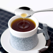 تحميل الصورة في عارض المعرض، Spoon pouring liquid into a cup of coffee on a checkered tablecloth