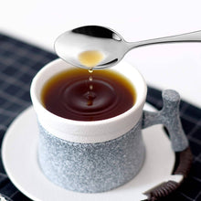 Load image into Gallery viewer, Spoon pouring liquid into a cup of coffee on a checkered tablecloth