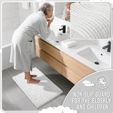 تحميل الصورة في عارض المعرض، Bathroom scene with a person using a bath mat, sink, and towel.