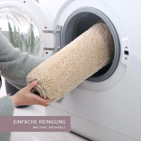 Person placing a beige rug into a washing machine with text 'EINFACHE REINIGUNG MACHINE WASHABLE'.