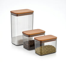 Load image into Gallery viewer, Set of three glass storage containers with wooden lids on a white background