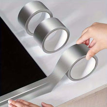 Load image into Gallery viewer, Person applying a roll of silver tape to a surface
