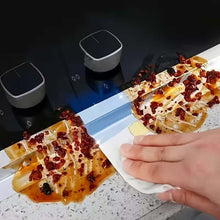 Load image into Gallery viewer, Two grilled items with red toppings on a white plate, with a hand holding a napkin, against a dark background.