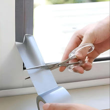 Load image into Gallery viewer, Person using scissors to cut a roll of tape on a window