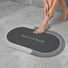 Load image into Gallery viewer, Person stepping onto a gray bath mat with 'Bathroom' text on a tiled floor.