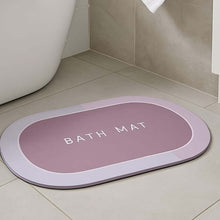 Load image into Gallery viewer, Pink oval anti-slip bath mat with textured surface and drainage holes, positioned on a bathroom floor.