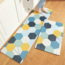 تحميل الصورة في عارض المعرض، Two rectangular anti-slip mats with a geometric pattern in multiple colors placed on a wooden floor, with a person's foot in motion above one of the mats.