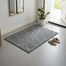 Load image into Gallery viewer, Gray doormat with leaf pattern on a light wooden floor, next to a plant and shoes.