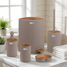 تحميل الصورة في عارض المعرض، A coordinated bathroom accessory set in a ribbed taupe finish with natural wood tops, including a tall trash can, smaller trash can, pump bottle, toilet brush, and lid, shown on a clean white background with a softly blurred bathroom interior behind them.