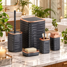 Load image into Gallery viewer, Set of black and rose gold bathroom containers with a soap bar and toothbrushes on a reflective surface.