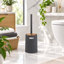 Load image into Gallery viewer, A modern dark gray ribbed cylindrical toilet brush holder with a black handle and a small wooden accent ring, shown against a blurred interior bathroom background.
