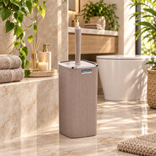Load image into Gallery viewer, A tall, ribbed gray toilet brush holder with a matching brush resting inside, shown in front of a bathroom scene background featuring a sink, mirror, and toilet.