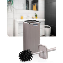 Load image into Gallery viewer, A modern stainless steel toilet brush holder with a matching toilet brush shown in front of a bathroom scene background. The holder has a ribbed metallic finish and a small visible brand plaque that appears to read TOTO.