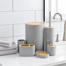 تحميل الصورة في عارض المعرض، A coordinated bathroom accessory set in light gray ribbed ceramic with natural wood tops, displayed on a white countertop beside folded towels and a sink. The set includes a tall lidded storage container, a toilet brush holder, a cup, a soap dispenser, a toothbrush holder, and a small round tray.
