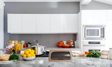 Load image into Gallery viewer, Modern kitchen with white cabinets, marble countertop, and various appliances.