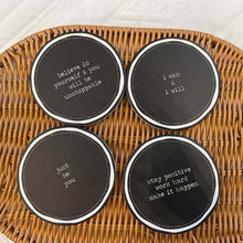 تحميل الصورة في عارض المعرض، Four black coasters with motivational phrases on a woven mat