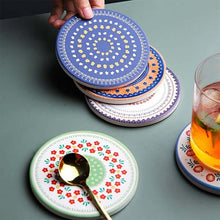 Load image into Gallery viewer, Set of colorful patterned coasters on a table with a glass of juice and a spoon.