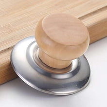 تحميل الصورة في عارض المعرض، A close-up of a kitchen utensil with a round light wood knob and a brushed silver metal base, resting on a light wood cutting board over a white surface.