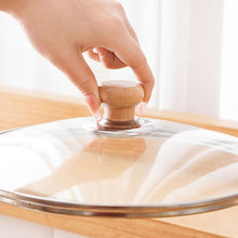 تحميل الصورة في عارض المعرض، Hand placing a wooden lid on a glass lid over a pot on a light background