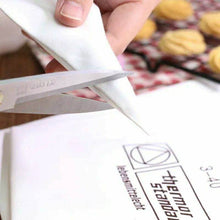 Load image into Gallery viewer, A hand cutting the tip of a cotton pastry bag for precise cupcake decoration.