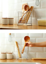 تحميل الصورة في عارض المعرض، Wooden utensils in a metal rack on a kitchen counter with a tiled backsplash.