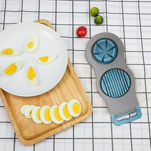 تحميل الصورة في عارض المعرض، Egg slicer with sliced eggs on a plate and cutting board on a checkered tablecloth.