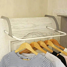 تحميل الصورة في عارض المعرض، Clothing rack with clothes on hangers against a neutral wall.