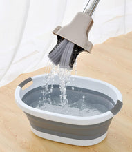 Load image into Gallery viewer, Collapsible bucket with a brush being rinsed under water on a wooden surface.