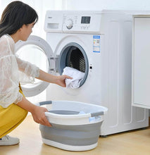 Load image into Gallery viewer, Woman using a washing machine with a collapsible laundry basket on a wooden floor.