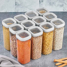 تحميل الصورة في عارض المعرض، A set of ten clear plastic storage jars with white lids, filled with various dry goods like pasta, beans, lentils, and chickpeas, arranged on a gray countertop.
