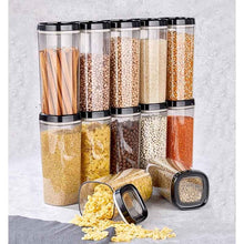 تحميل الصورة في عارض المعرض، Eight clear plastic storage jars with black lids are arranged on a light gray textured surface, filled with various dry goods like pasta, beans, lentils, and spices. Two jars in the front are tipped over with their contents spilled out.