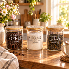 تحميل الصورة في عارض المعرض، Three glass jars with wooden lids labeled 'Coffee', 'Sugar', and 'Tea' on a kitchen counter.