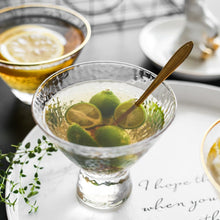Load image into Gallery viewer, Cocktail with lime wedges and a spoon in a glass on a marble surface.