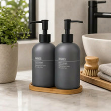 Load image into Gallery viewer, Two grey glass soap dispensers labelled HANDS and DISHES on a wooden tray by a basin