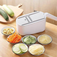 Load image into Gallery viewer, A white multifunctional vegetable grater with adjustable blades and a handle, displayed on a kitchen counter with sliced vegetables around it.
