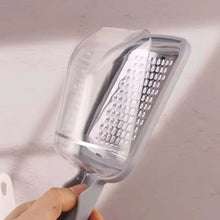 تحميل الصورة في عارض المعرض، Hand holding a clear grater against a neutral background