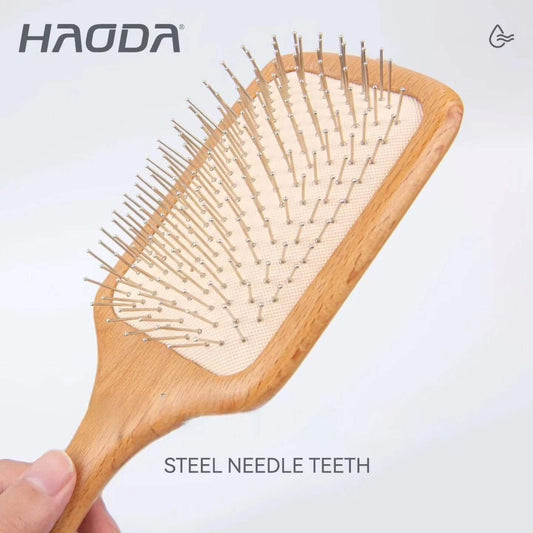 Hairbrush with steel needle teeth held by a hand, branded 'HAODA' on a light gray background.