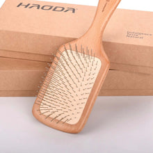 تحميل الصورة في عارض المعرض، Wooden paddle brush with natural bristles on a light gray background, branded 'HAODA'.