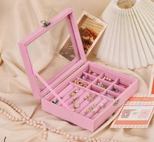 Load image into Gallery viewer, Pink jewelry box with compartments filled with jewelry on a beige surface.